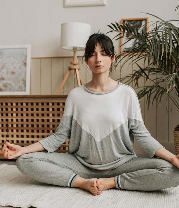 Woman holding a calm yoga pose in a dark room with silver light.